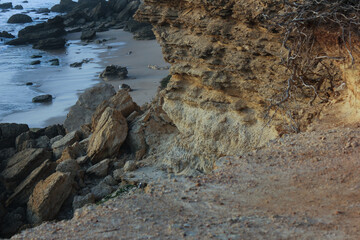 Eroding cliff face overlooking sandy beach and ocean waves