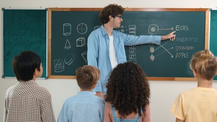 Caucasian smart teacher teach while student standing at blackboard and listening instructor at...
