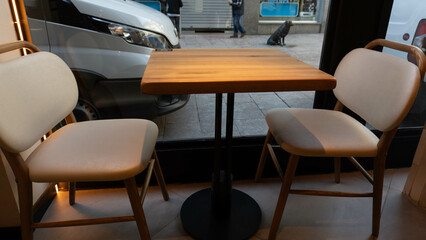 a table and two empty chairs inside a shop next to a window where you can see the street