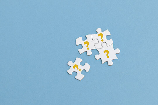 The image features four white puzzle pieces connected together on a blue background. Each piece has an yellow question mark, symbolizing mystery, problem-solving, or searching for answers.