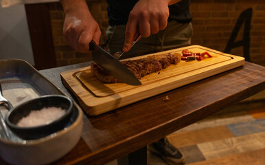 Person cutting a piece of meat fresh off the grill with a knife and fork