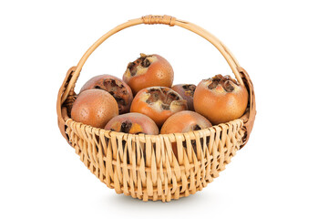 Brown fresh medlars in a wicker basket isolated on white background. Mespilus germanica close-up