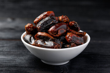 Dried sweet pitted dates in white bowl. Healthy food