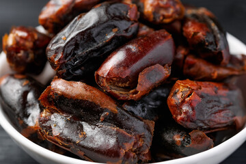 Dried sweet pitted dates in white bowl. Healthy food