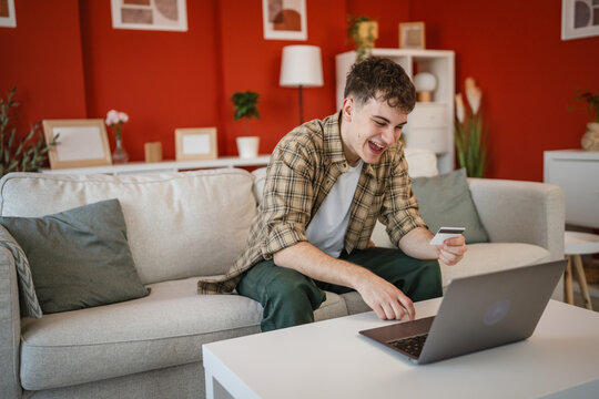 young man enjoy at online shopping with credit card and laptop at home
