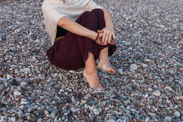 Woman sitting on a pebble beach enjoying the calming waves and natural surroundings