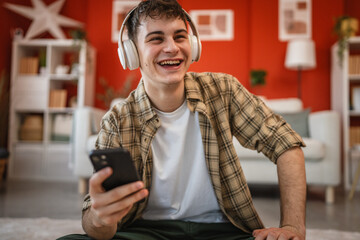 man listen music on headphones and browse his mobile phone at home