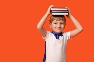 Cute little boy dressed as superhero with books on orange background. Library Lovers Day