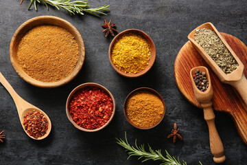 Composition with different aromatic spices and fresh rosemary on dark background