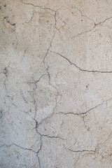 Imagen vertical de una pared de cemento gris con grietas ideal para textura