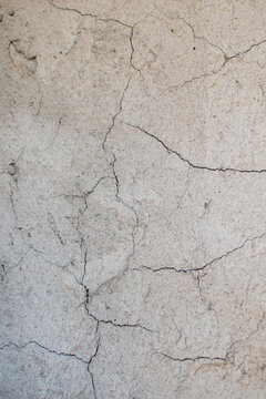 Imagen vertical de una pared de cemento gris con grietas ideal para textura