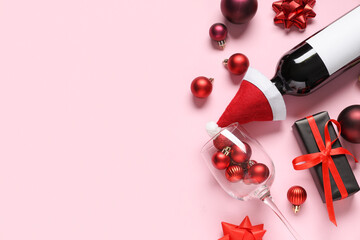 Composition with bottle of wine, gift box and Christmas decorations on pink background