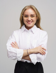 Young woman with glasses smiling confidently, dressed in a white shirt against a simple background