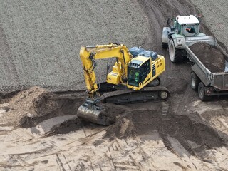 Bagger verlädt Erde auf einer Baustelle auf einen Traktor mit Muldenkipper, Tiefbau, Straßenbau,...