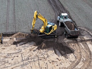 Bagger verlädt Erde auf einer Baustelle auf einen Traktor mit Muldenkipper, Tiefbau, Straßenbau,...
