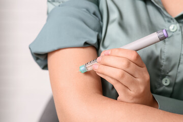 Diabetic woman giving herself insulin injection in office, closeup