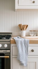 Classic coastal kitchen featuring white beadboard cabinets and butcher block countertop bathed in soft morning light with minimalistic decor