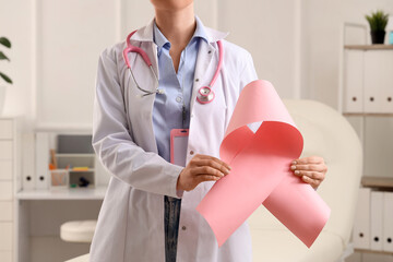 Female doctor with pink ribbon in clinic. Breast cancer awareness concept