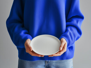 Foto de manos sosteniendo un plato blanco sencillo