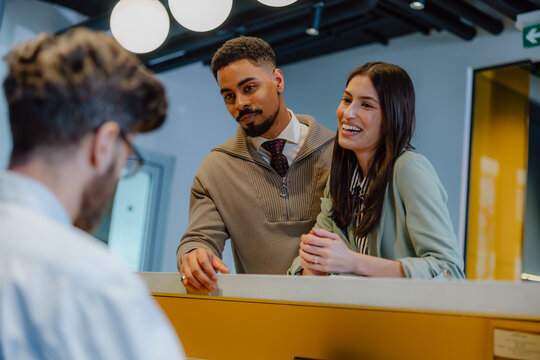 Friendly Worker Helping Clients at a Modern Office Reception Desk