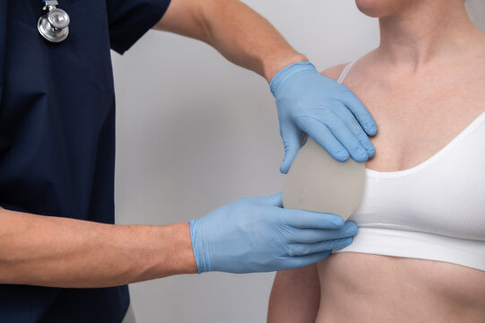 doctor and patient, exam, consultation in clinic office, holding breast enlargement implant in hands, plastic surgery, beauty enhancement, medical Mammoplasty and plastic surgery, mastopexy