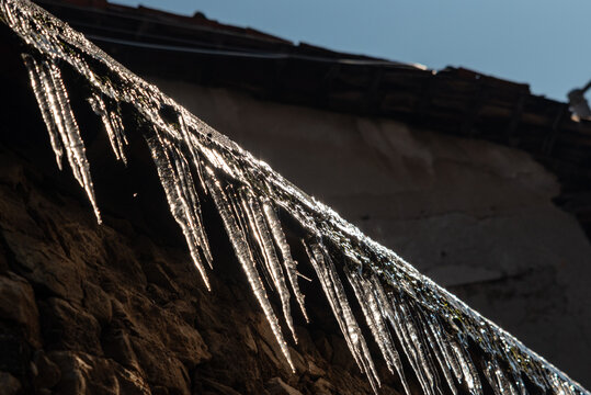 "Icicles on an Old Stone House Roof in Winter Sunlight"