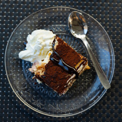 Exquisite classic dessert Tiramisu with airy sponge texture, delicate coffee taste and light mascarpone cream traditionally sprinkled with cocoa, served on plate. Italian style confectionery