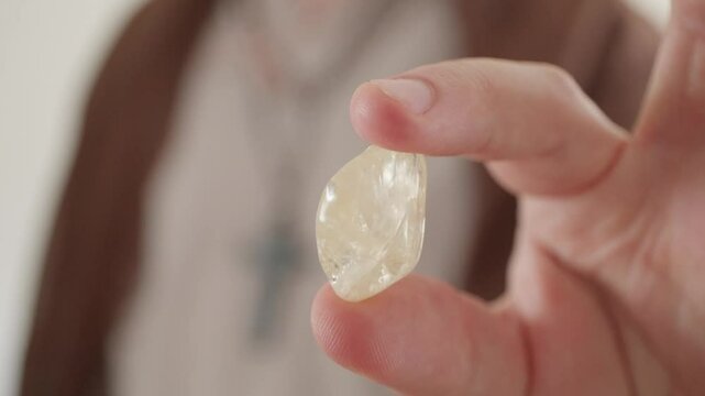 A priest in traditional dress holding a citrine stone