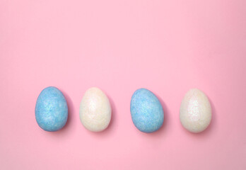 Festive Easter eggs in blue and white arranged in a row on a pastel pink background. Minimalist holiday concept, perfect for seasonal designs, greeting cards, and marketing.