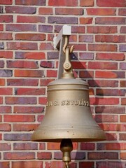 Obraz premium Glocke hängt vor Backsteinmauer