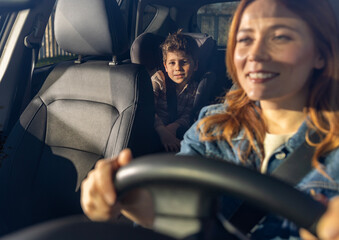 Woman driving car with child in backseat on a sunny day