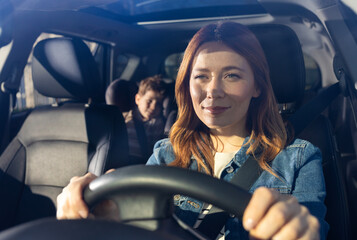 Woman driving car with child in backseat on a sunny day