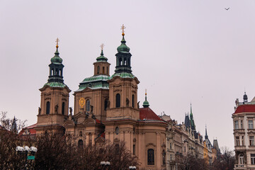 Church of St Nicholas dominating Prague cityscape under cloudy sky