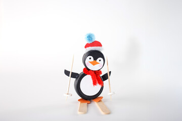 DIY penguin and snowman crafts made from plastic bottle caps with pipe cleaner accessories on white background. Studio shot. Winter and Christmas craft idea for design, print, kids activities,