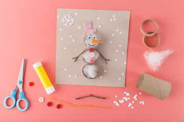 Fun craft project with a snowman made from various materials like cotton stuffing, buttons, and twigs. Suitable for holiday decorations, craft supplies, or children creative activity