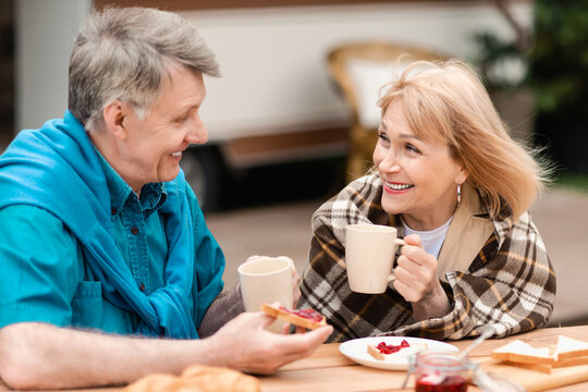 Affectionale elderly couple having coffee with toasts and jam for lunch in countryside during vacation