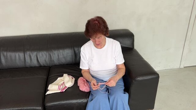 senior Women in causal clothes is engaged in needlework.