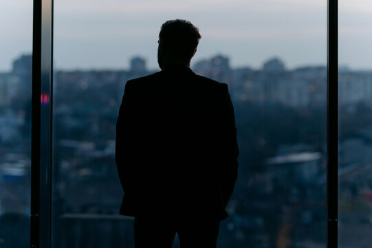 Contemplative Businessman Overlooking a Cityscape at Dusk
