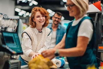 Happy customer paying for groceries at supermarket checkout,