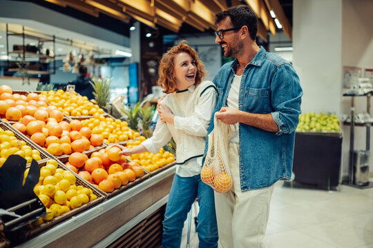 Happy couple choosing fresh citrus fruits at grocery store