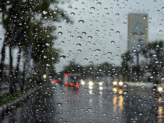 blurry night view of wet car windows due to rain, rainy season in tropical areas
