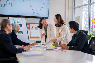 A group of people are sitting around a table with a whiteboard behind them