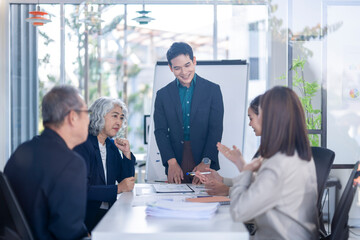 A group of people are sitting around a table with a white board in front of them