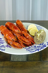 Whole lobsters from Maine on a nautical dish with a baked potato