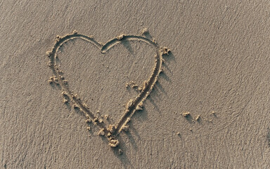 close-up of a heart drawn in the sand. beach vacation holiday background. wedding save the date rsvp design element engagement or proposal theme. valentine message.