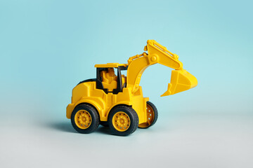 yellow mini excavator toy in action on cyan background