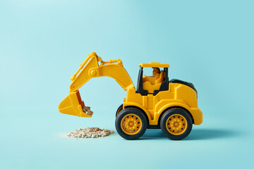 excavator toy carrying debris on cyan background