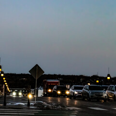 evening city scene on a main city thoroughfare road with a trail of headlights in traffic. bokeh light effect. line of lanterns for illumination.