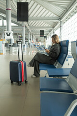 young latina girl working on her tablet from the airport waiting room