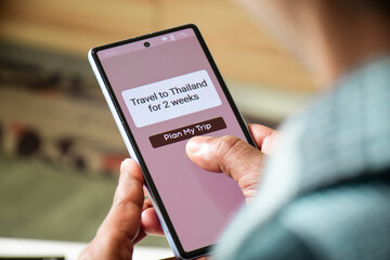 Man using mobile applications for trip planning to Thailand. Travel itinerary making using artificial intelligence concepts to save time. Selective focus.